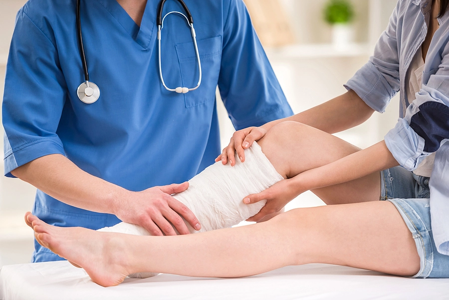 Doctor treating victim's injured leg who sought medical attention after a car accident