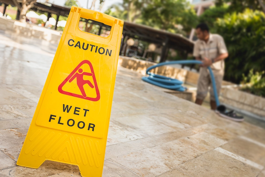 Property owner polishing floor with a caution sign out to avoid being held responsible if someone slips and falls